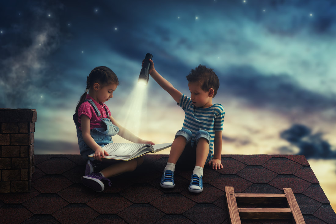 Boy holding flashlight and girl reading. Both are sitting on the roof of house at night