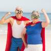 Superhero couple in retirement on beach in power pose