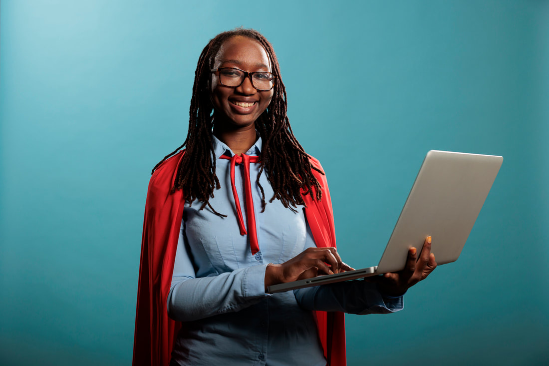 Young professional woman wearing cape, smiling and holding a computer.