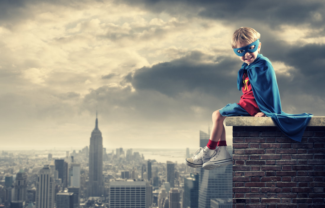 Boy wearing hero cape sitting outside in the city