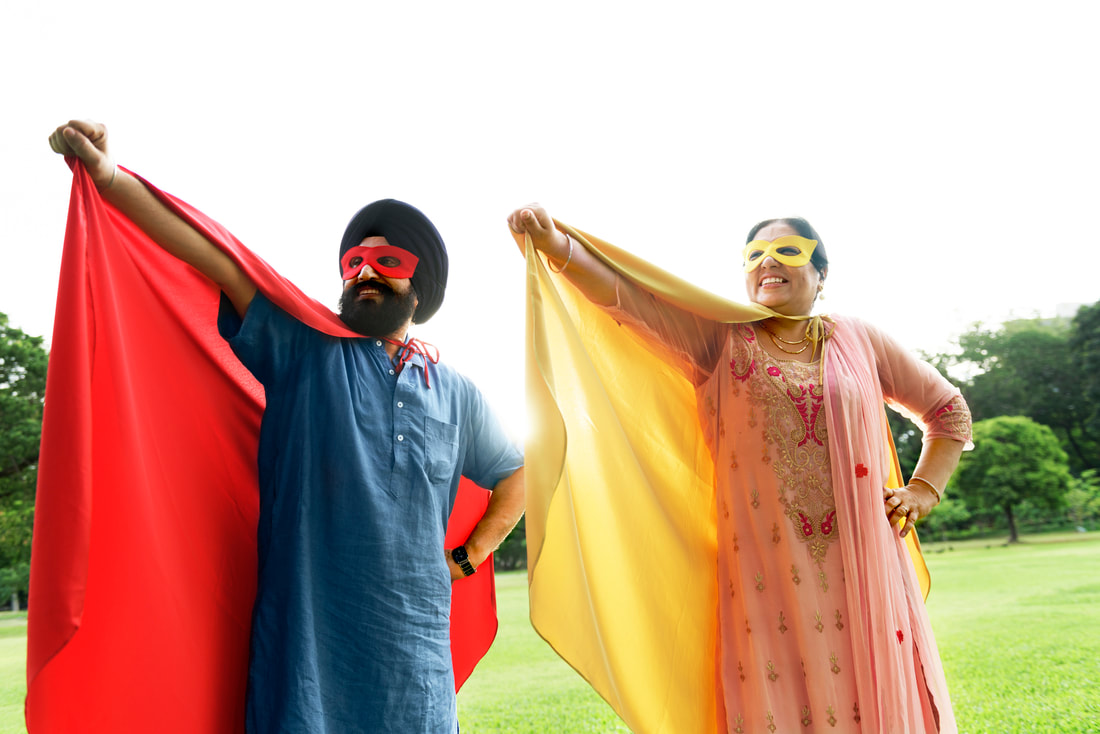 Couple wearing capes with arms outstretched.
